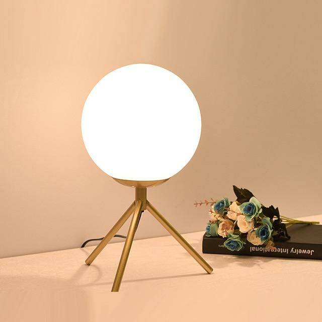 Design table lamp with golden arms and glass ball