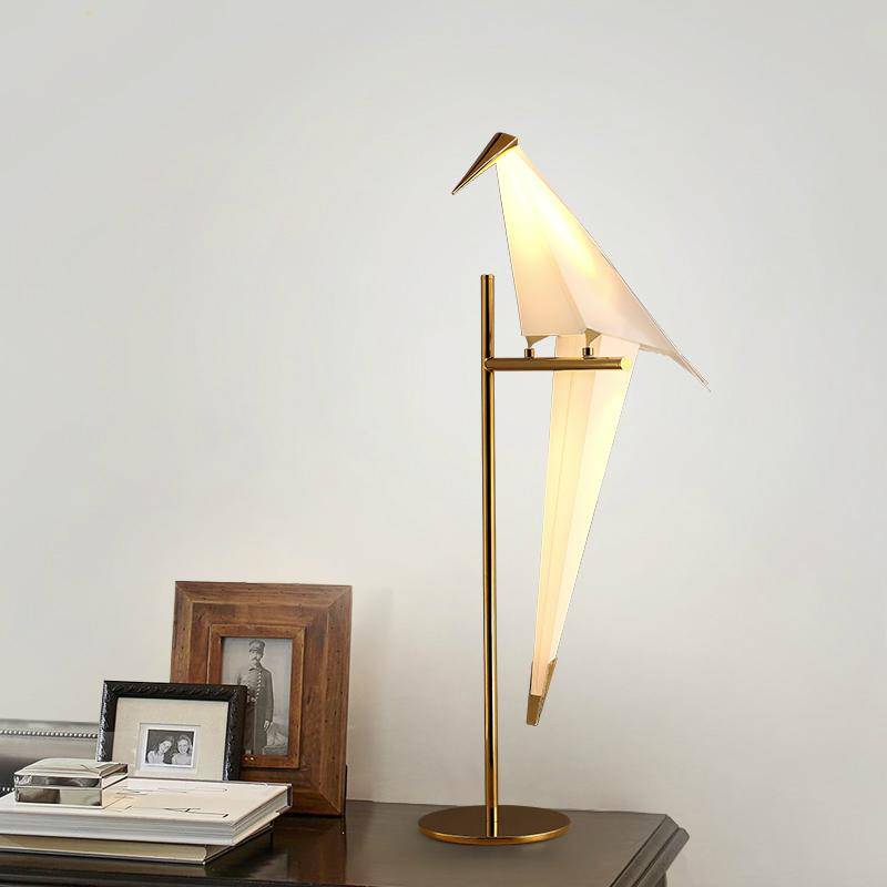 Lámpara de mesa en forma de pájaro sobre una rama dorada