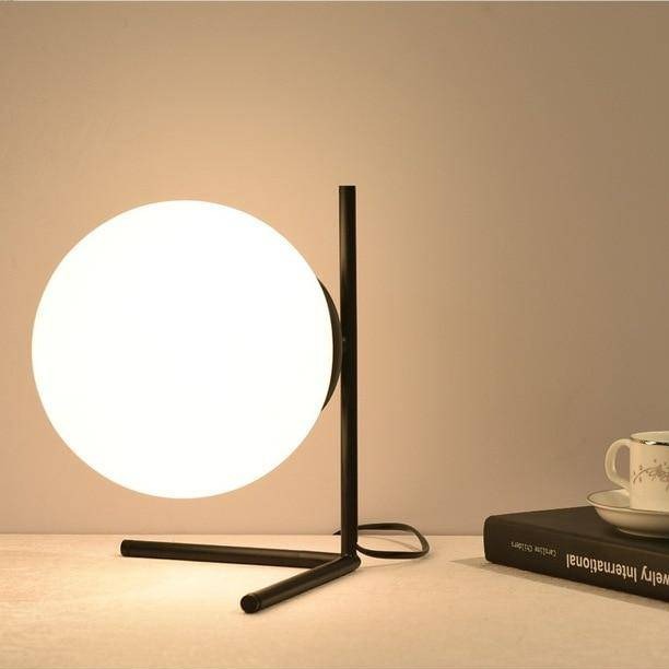 Design table lamp with golden arms and glass ball