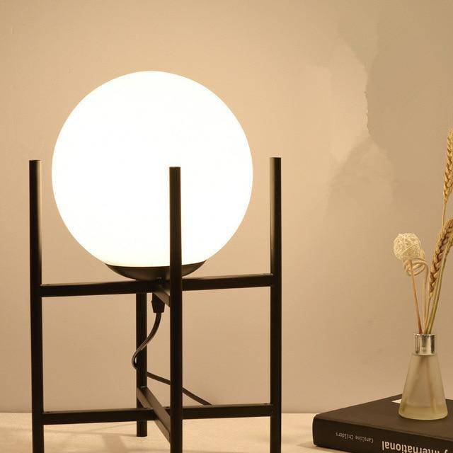 Design table lamp with golden arms and glass ball