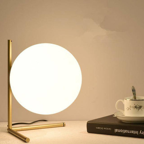 Design table lamp with golden arms and glass ball