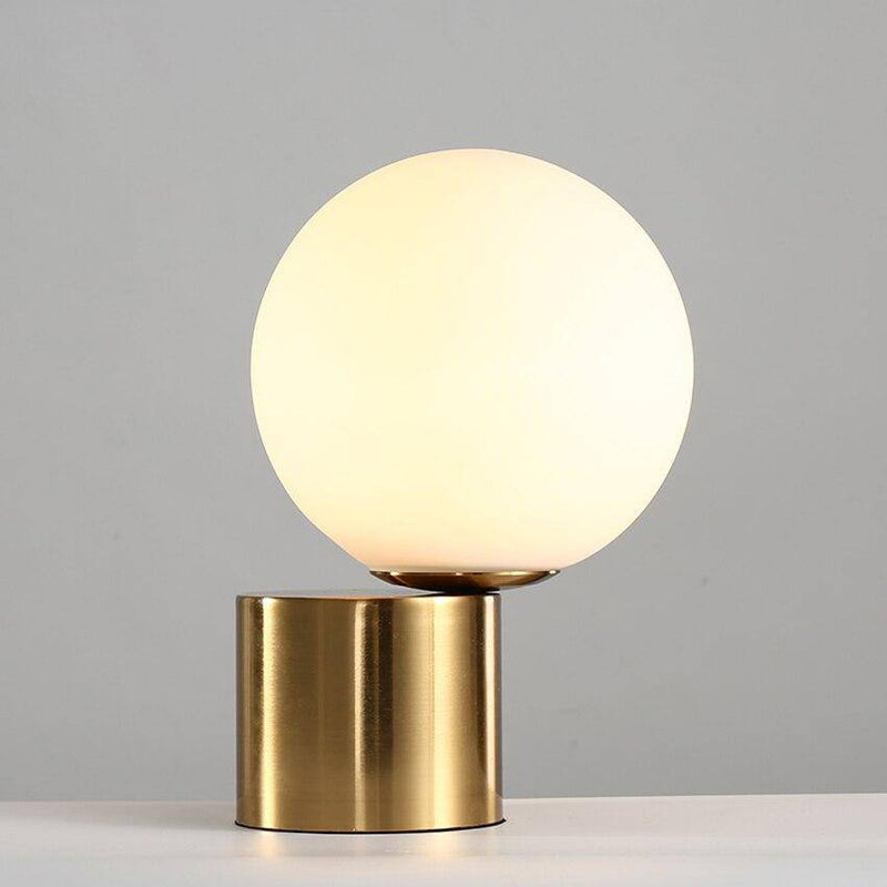 Bedside lamp with gold base and modern glass ball