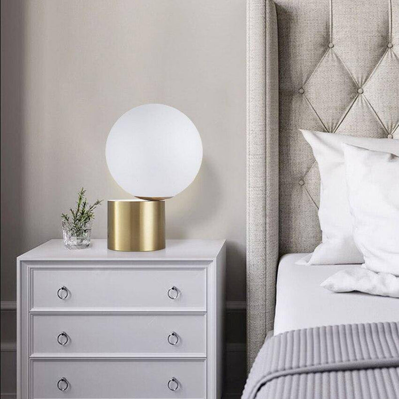 Bedside lamp with gold base and modern glass ball