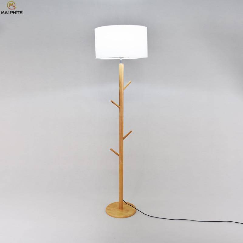 Lámpara de pie con pantalla de tela y base de madera con ramas