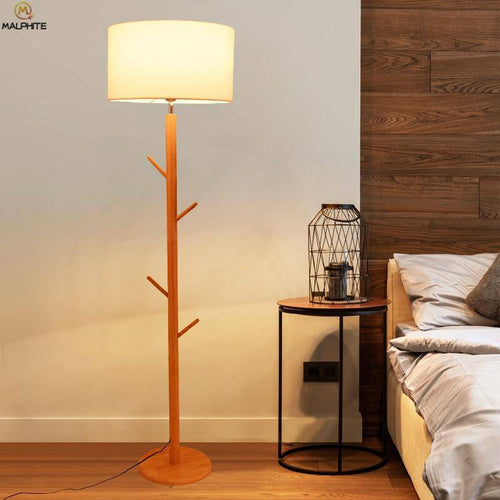 Lámpara de pie con pantalla de tela y base de madera con ramas